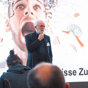 Widerstandsfähigkeit ist das grundlegende Prinzip, das sich durch seinen Vortrag zog. Sich an Umstände anzupassen, die man nicht kontrollieren kann, und positive Änderungen dort zu schaffen, wo es möglich ist.